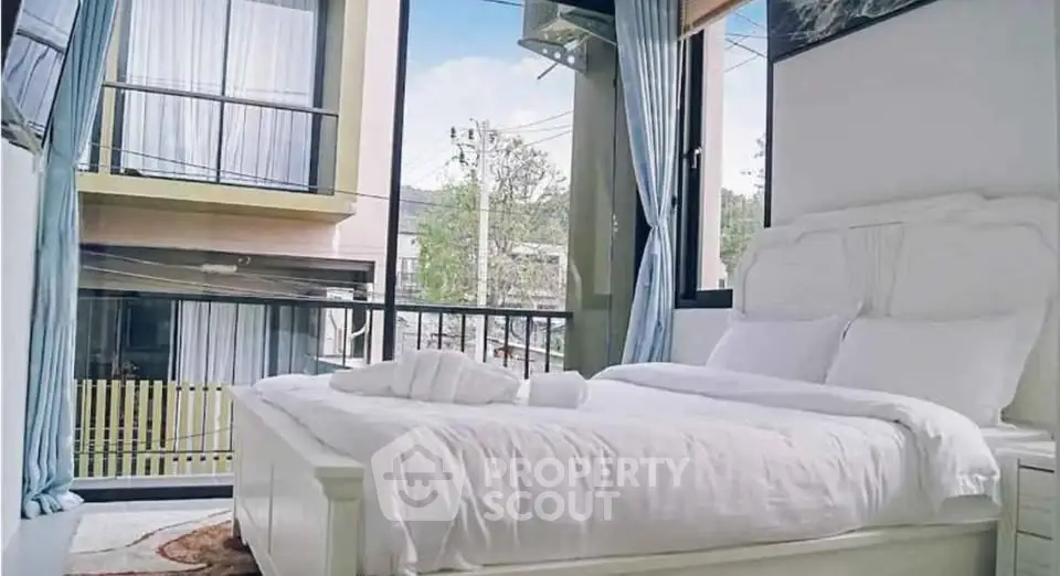 Spacious bedroom with large windows offering a scenic view, featuring elegant white bedding and modern decor.