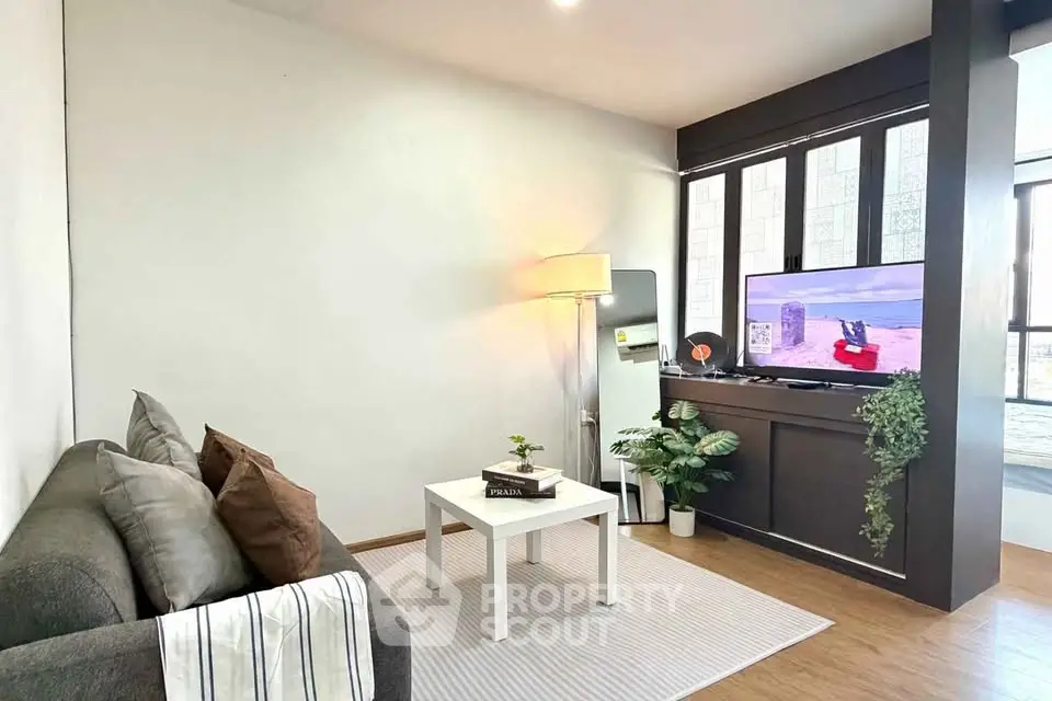 Cozy living room with modern decor, featuring a comfortable sofa, stylish lamp, and entertainment setup.