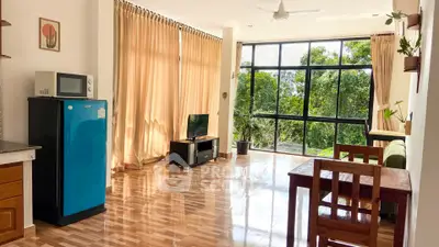 Spacious living room with large windows and natural light, featuring modern furniture and a serene view.
