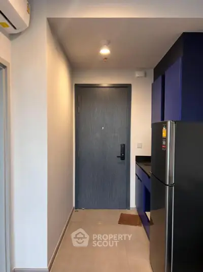 Modern apartment entrance with sleek kitchen and stainless steel fridge