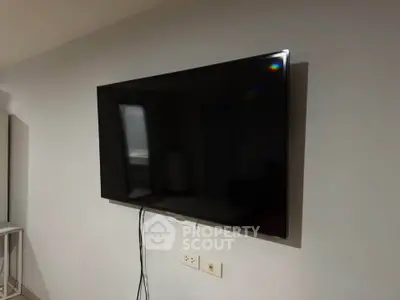 Modern living room with wall-mounted flat-screen TV and sleek decor.