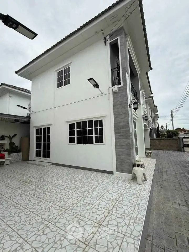 Modern two-story house with spacious tiled driveway and contemporary design.