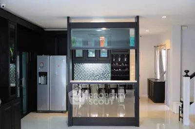 Modern kitchen with sleek black cabinetry and stainless steel appliances, featuring a stylish open layout and breakfast bar.