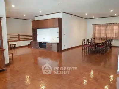 Spacious living room with polished wooden floors and elegant dining area.
