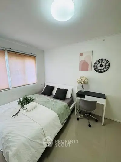 Cozy bedroom with modern decor, featuring a comfortable bed, desk, and stylish wall clock.