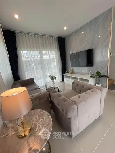Elegant living room with plush sofas, marble table, and wall-mounted TV in modern apartment.