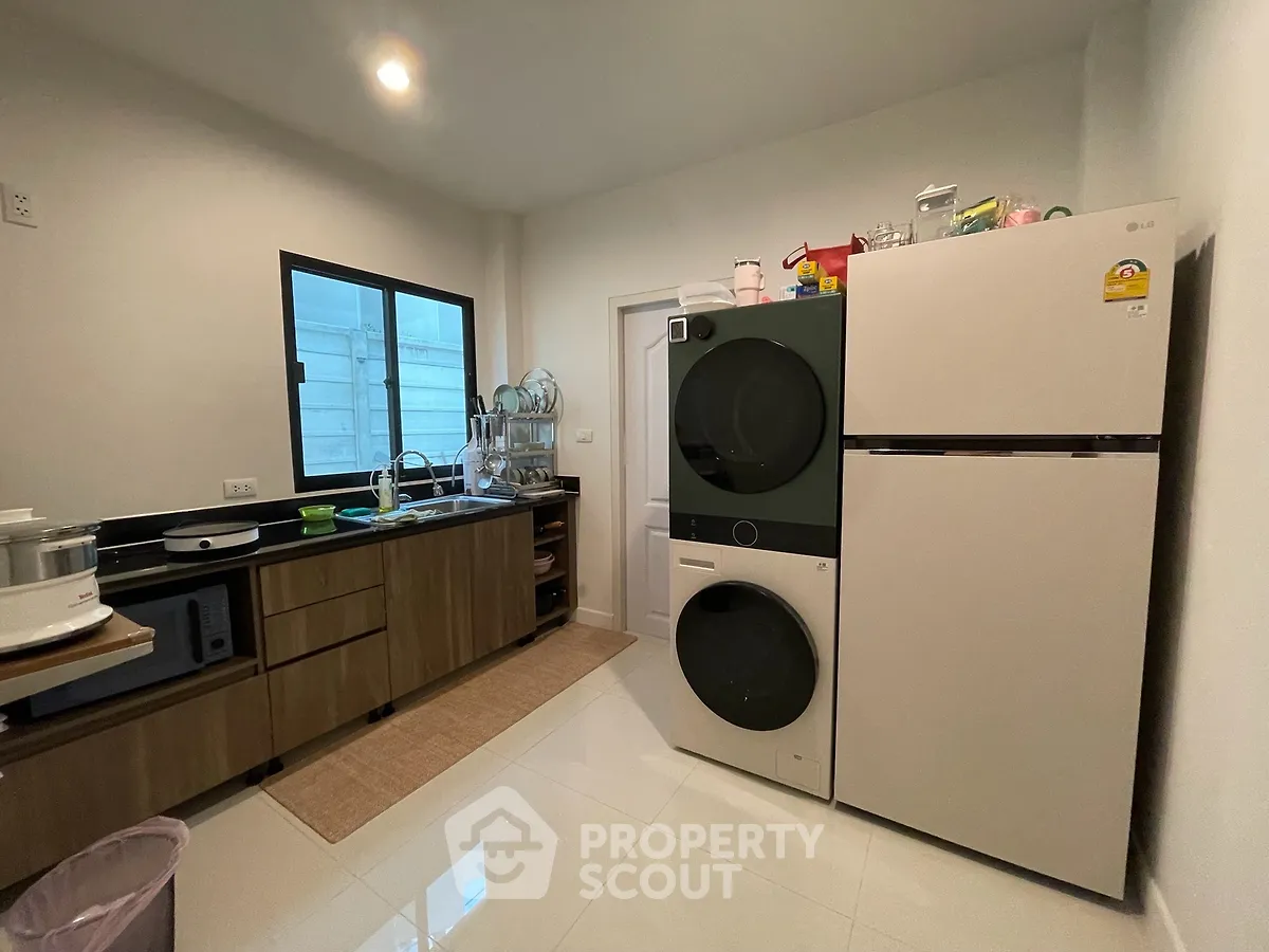 Modern kitchen with sleek appliances and ample storage space, featuring a washing machine and dryer combo.