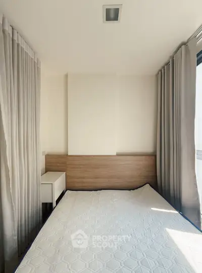 Modern bedroom with natural light and minimalist design, featuring a cozy bed and elegant curtains.