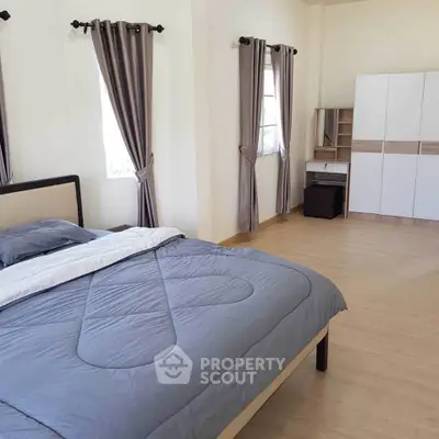 Spacious bedroom with modern decor and ample natural light, featuring a comfortable bed and stylish curtains.