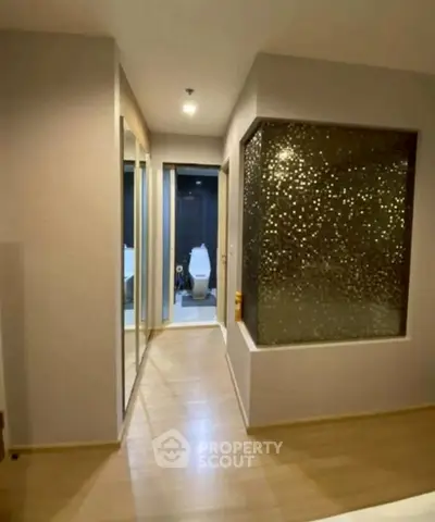 Modern apartment hallway with stylish bathroom and mirrored closet doors.