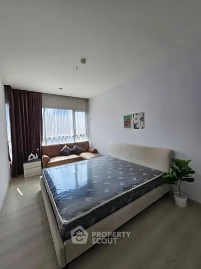 Spacious bedroom with large window and modern decor in a stylish apartment.