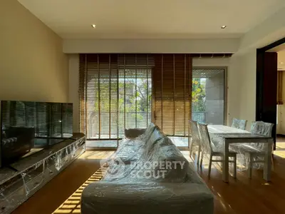 Modern living room with large windows and balcony access, featuring stylish furniture and natural light.