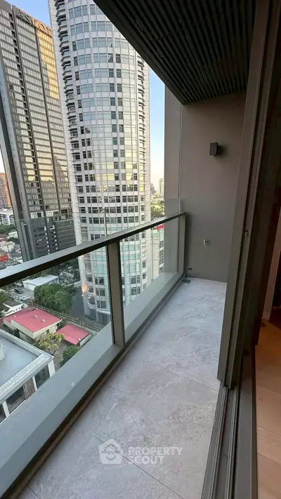Modern high-rise balcony with cityscape view and sleek glass railing.