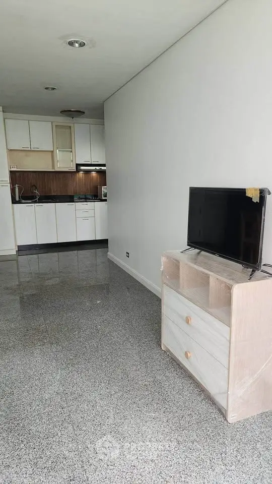 Spacious open-plan living room with modern kitchen and sleek flooring, perfect for contemporary living.