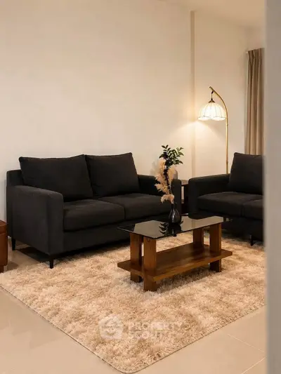 Elegant living room with dark sofas, stylish lamp, and cozy rug creating a warm, inviting atmosphere.