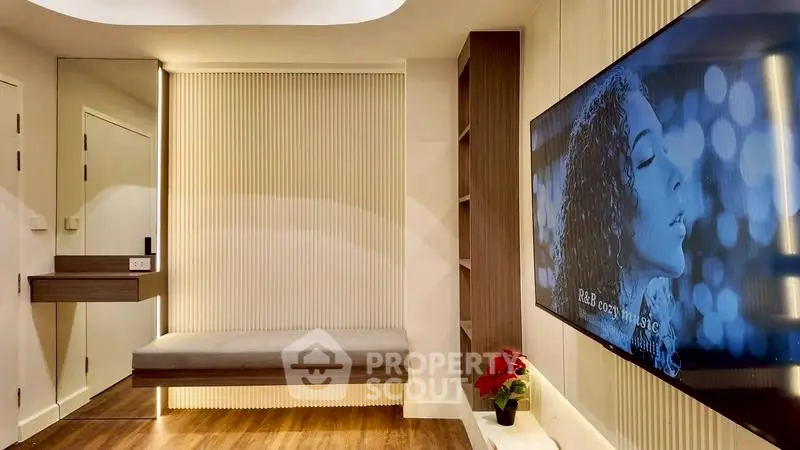 Modern living room with sleek design and large wall-mounted TV, featuring elegant wood flooring.