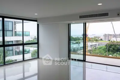 Spacious modern living room with large windows and balcony offering stunning city views.