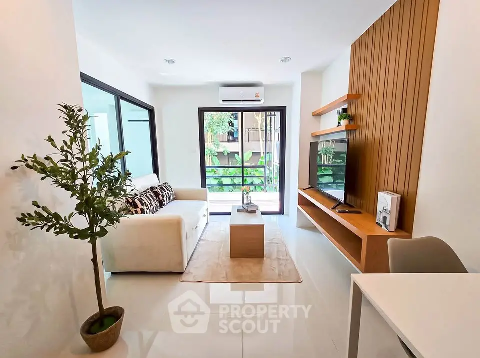 Modern living room with sleek design, featuring a cozy sofa, wall-mounted TV, and large window with garden view.