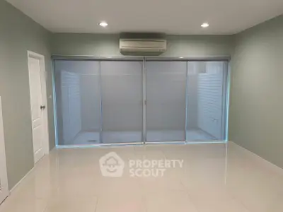 Spacious modern living room with large sliding glass doors and air conditioning.