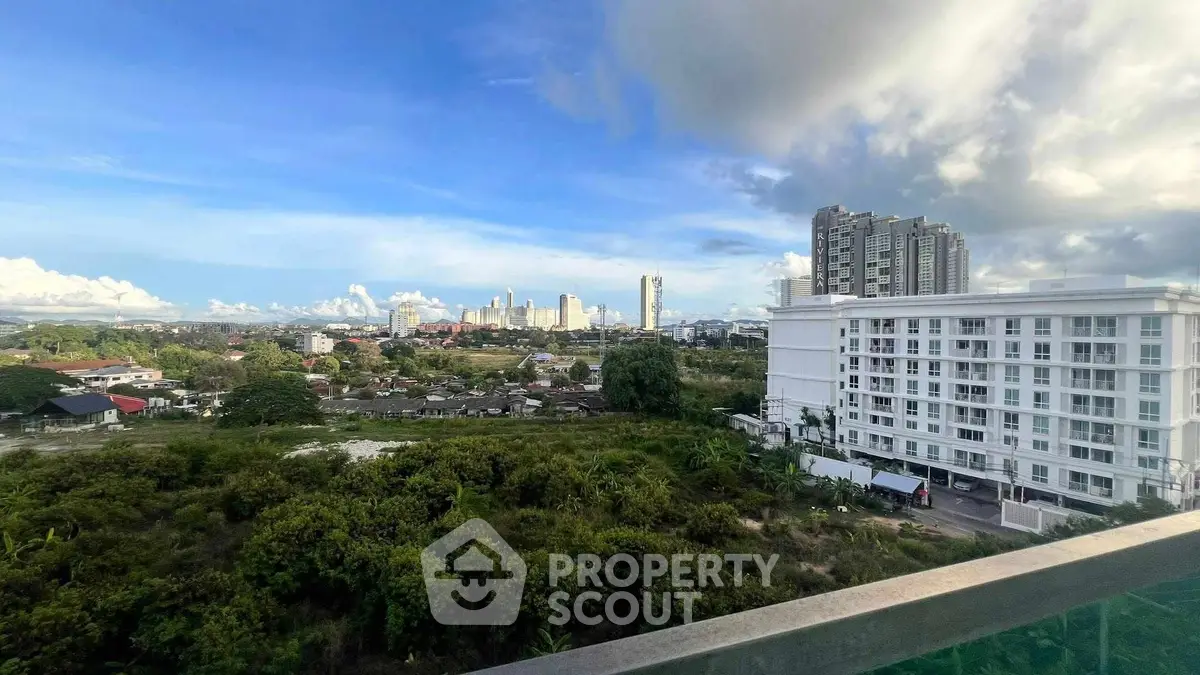 Stunning cityscape view from a high-rise balcony overlooking lush greenery and urban skyline.
