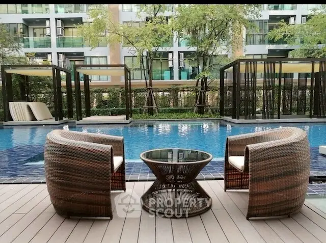 Luxurious poolside seating area with modern wicker chairs and glass table, perfect for relaxation.