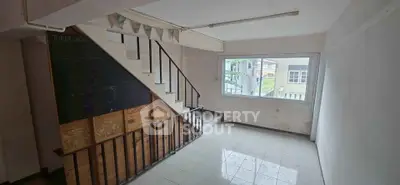 Spacious interior with large window and staircase, ideal for creative renovations.