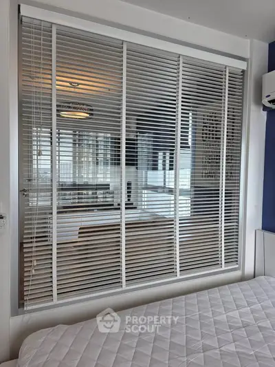 Modern bedroom with window blinds and air conditioning, offering a glimpse into a stylish living area.