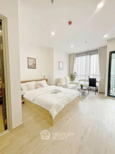 Spacious modern bedroom with large windows and cozy seating area