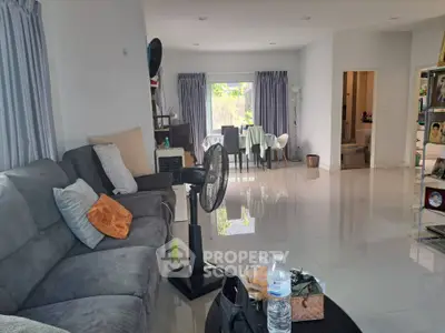 Spacious living room with modern decor and natural light, featuring a cozy seating area and dining space.