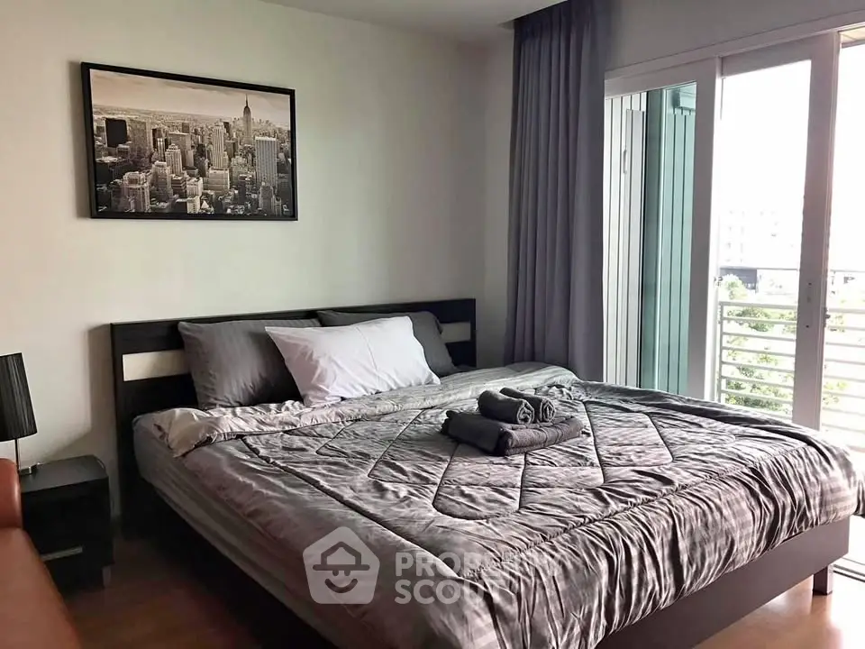 Modern bedroom with stylish decor and balcony access in urban apartment.