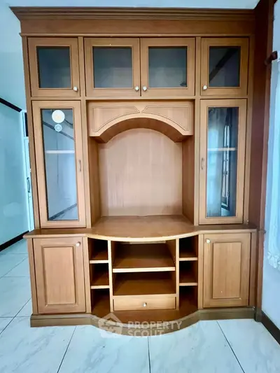 Elegant wooden entertainment center with glass cabinets in a spacious living room.