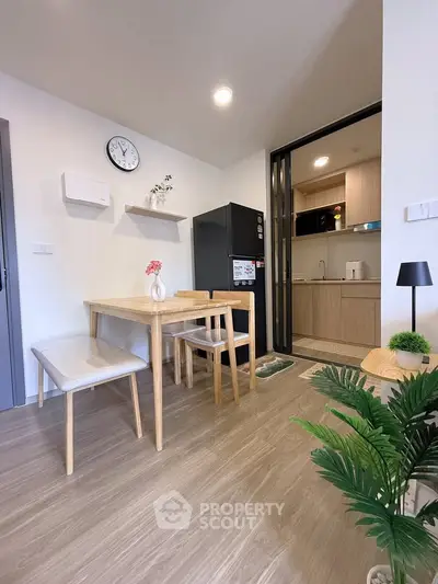 Modern dining area with wooden furniture and open kitchen layout in a cozy apartment.