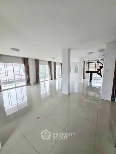 Spacious open-plan living area with large windows and glossy tiled floors, perfect for modern living.