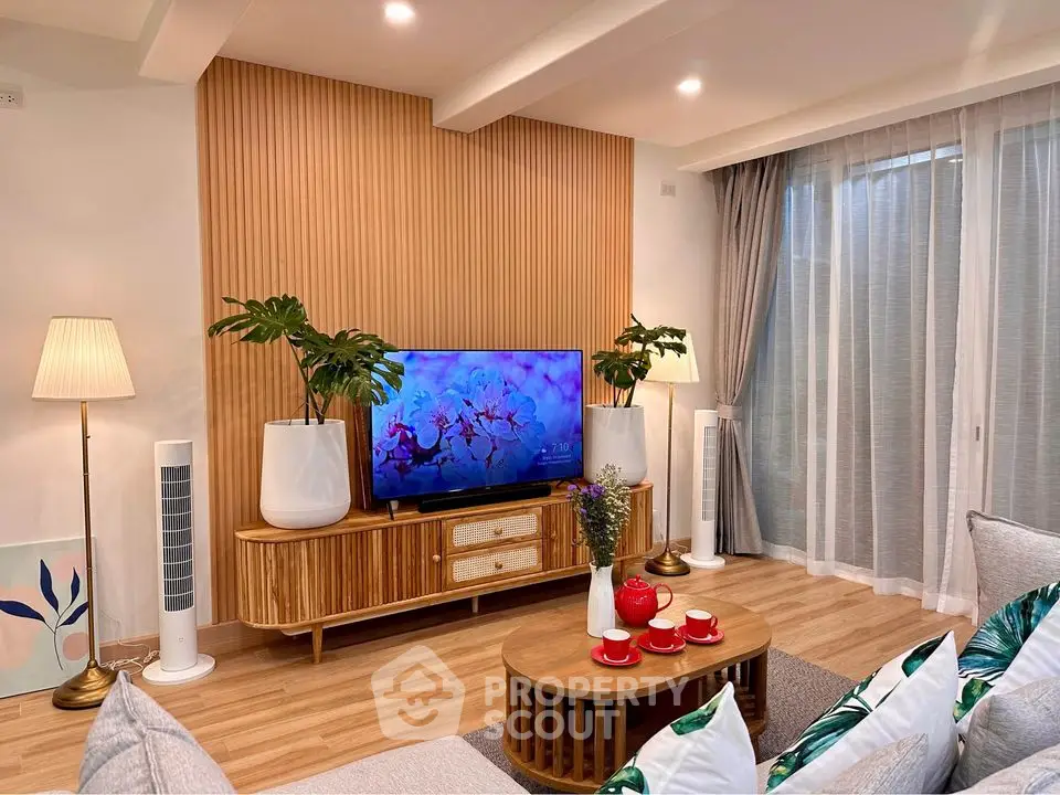 Stylish living room with modern decor and wooden accents, featuring a cozy seating area and large TV.