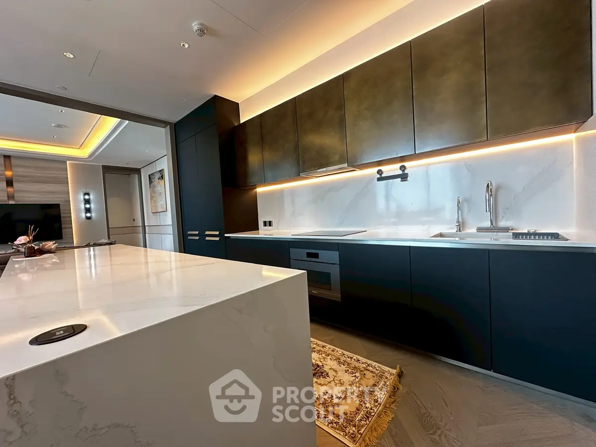 Luxurious modern kitchen with sleek cabinetry and marble countertops in upscale apartment.
