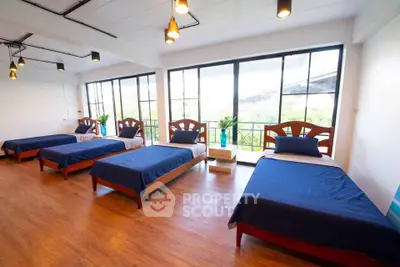 Spacious bedroom with multiple beds and large windows offering natural light and garden view.