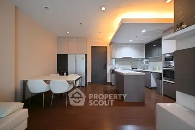 Modern open-layout kitchen and dining area with sleek design and warm lighting.
