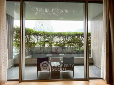 Spacious balcony with modern seating and lush greenery view, perfect for relaxation and outdoor enjoyment.