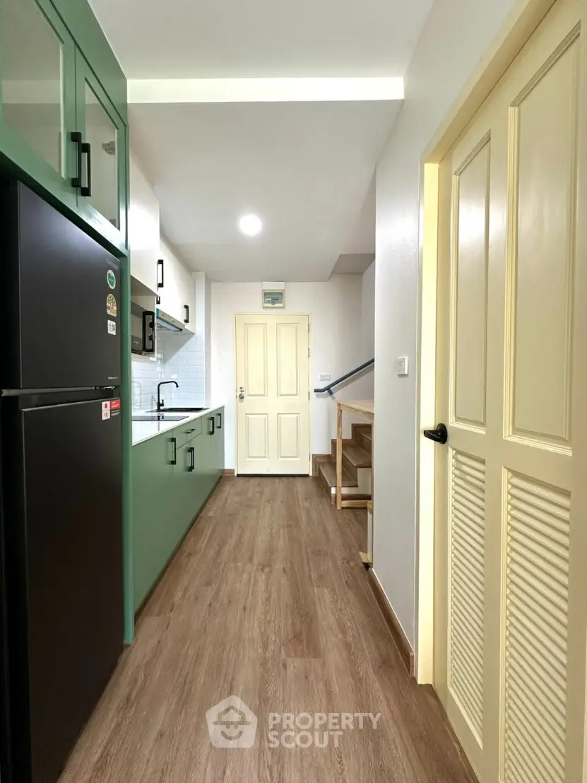 Modern kitchen with green cabinets and wood flooring in a cozy apartment