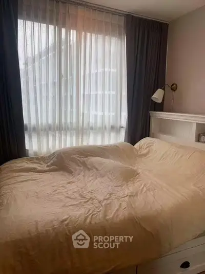 Cozy bedroom with large window and elegant curtains, perfect for relaxation and comfort.