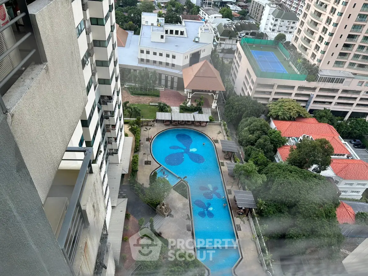 Stunning aerial view of a luxurious residential pool surrounded by lush greenery and modern buildings.