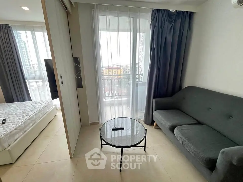 Modern studio apartment with balcony view and cozy living area.