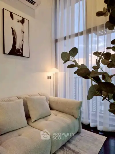 Stylish living room with cozy sofa and elegant decor, featuring floor-to-ceiling windows and modern art.