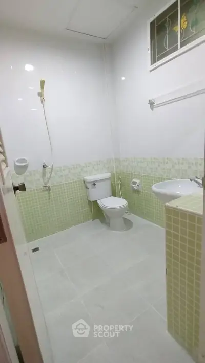 Modern bathroom with green tile accents and white fixtures