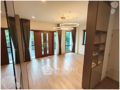 Spacious modern living room with elegant lighting and large windows opening to a balcony.