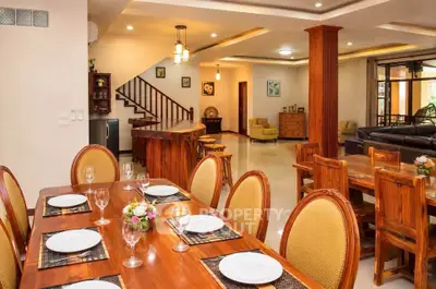 Luxurious open-plan dining and living area with elegant wooden furniture and modern lighting.