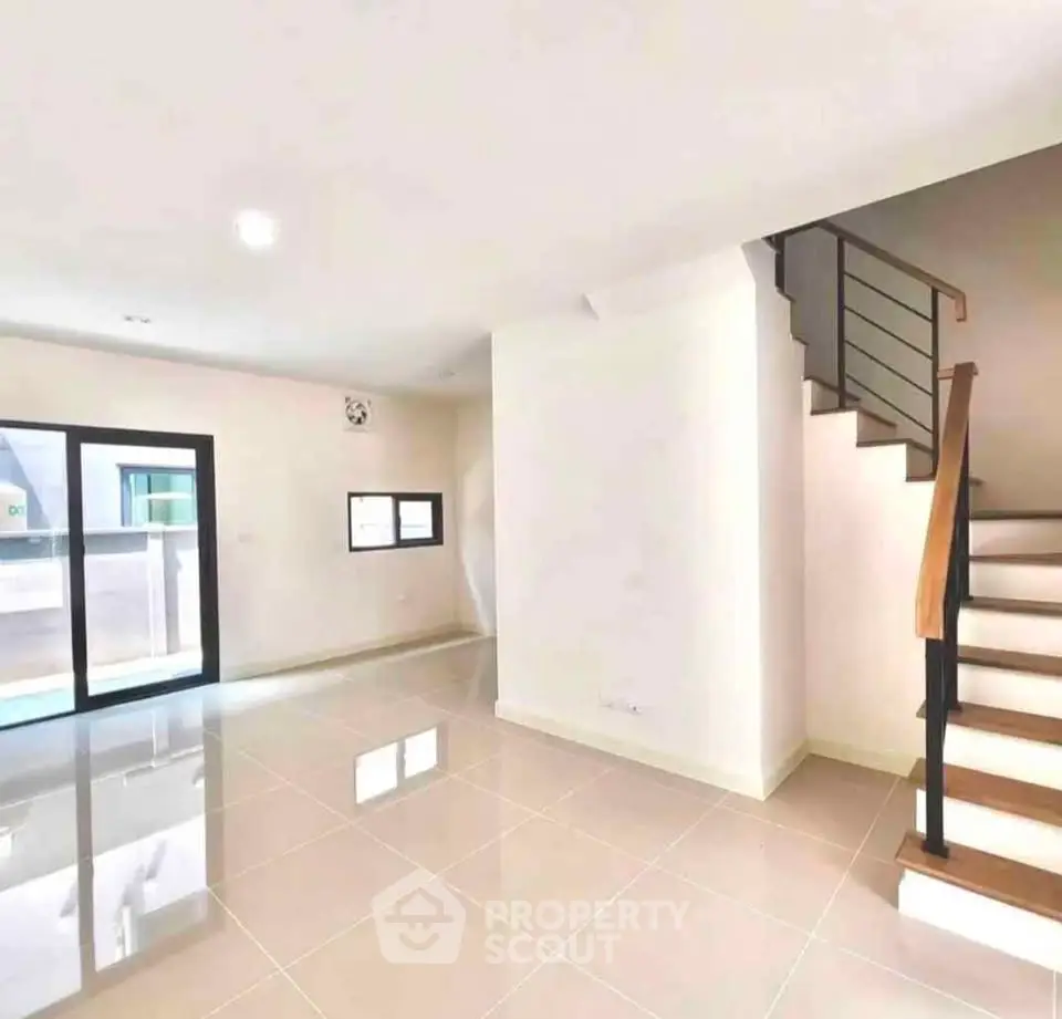 Spacious modern living room with glossy tiled floors and elegant staircase, perfect for contemporary living.