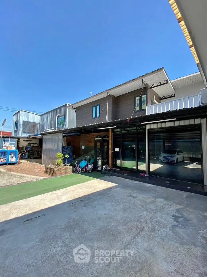 Modern industrial-style building with spacious parking area under clear blue sky.