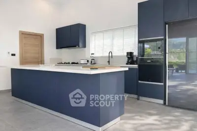 Modern kitchen with sleek blue cabinets and island, featuring large window with scenic view.