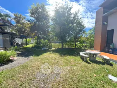 Spacious backyard with lush greenery and outdoor seating area under clear blue sky.